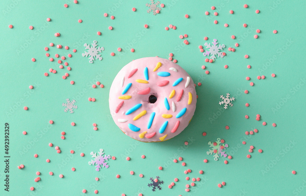 Sweet donut and sprinkles on color background