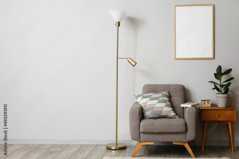 Interior of modern room with standing lamp, armchair and table