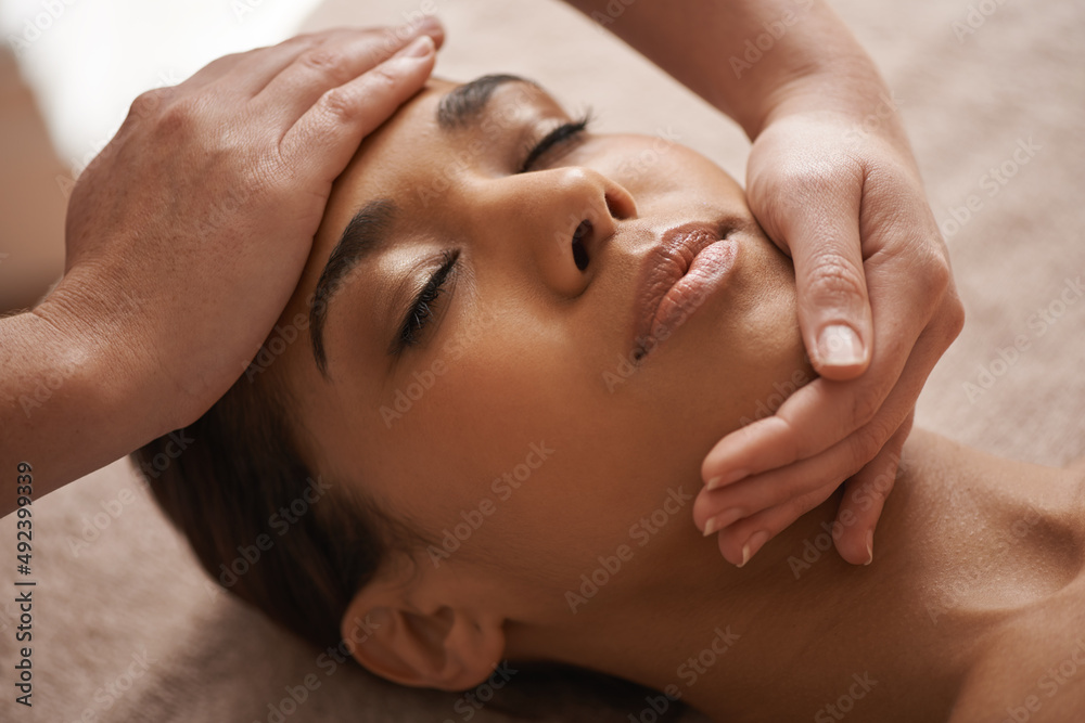 Massaging the body and mind. Shot of a beautiful young woman getting a head massage at a spa.