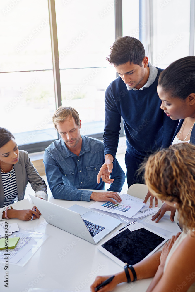 Outlining new strategies. Shot of a group of coworkers working together on a laptop in an office.