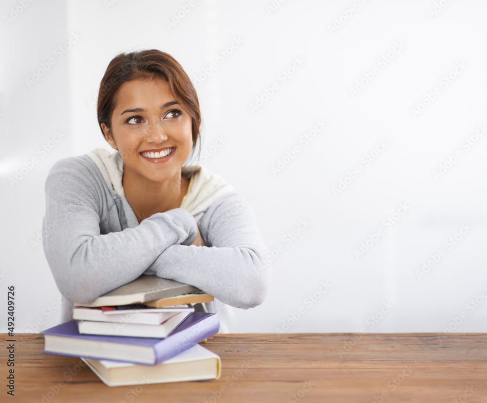 Finding the solution to a problem. Shot of a beautiful college student leaning on her books at her d