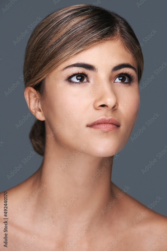 Positively beautiful. A cropped shot of a beautiful young woman looking up isolated on grey.