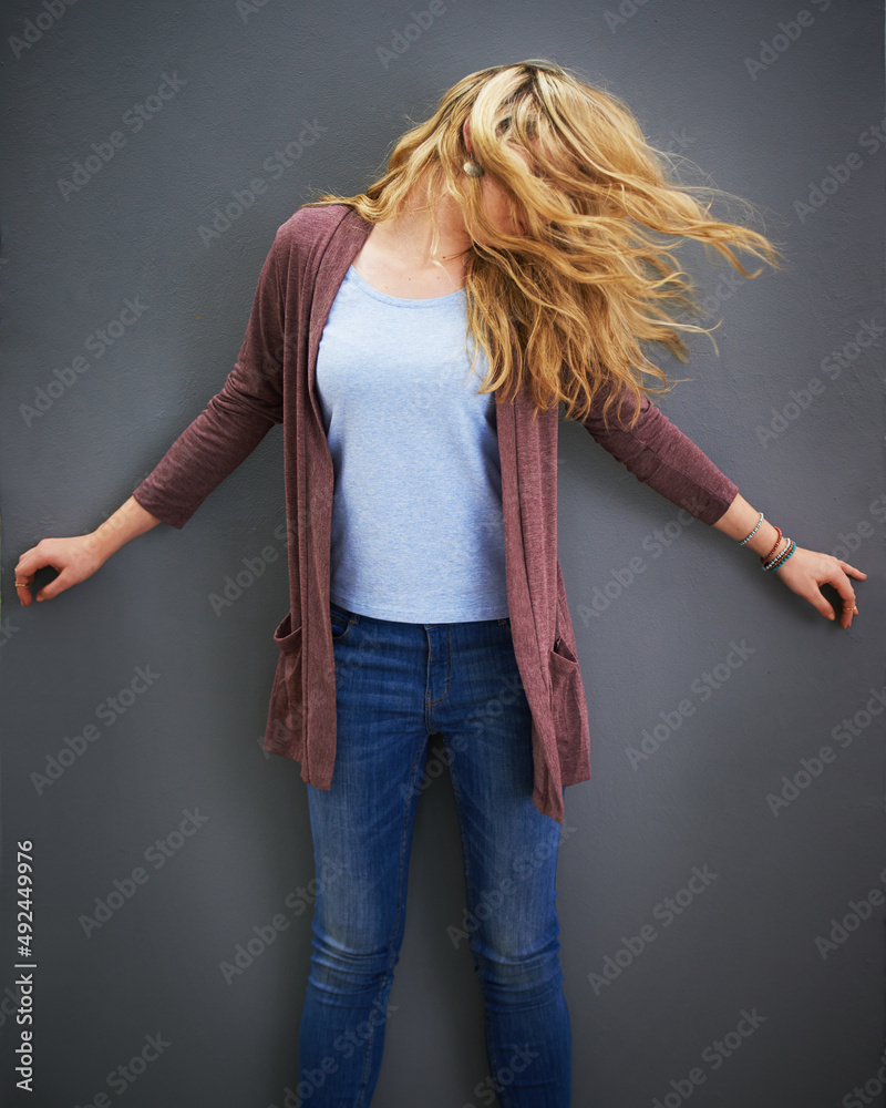 Let your hair down. Shot of a young woman standing against a gray background.