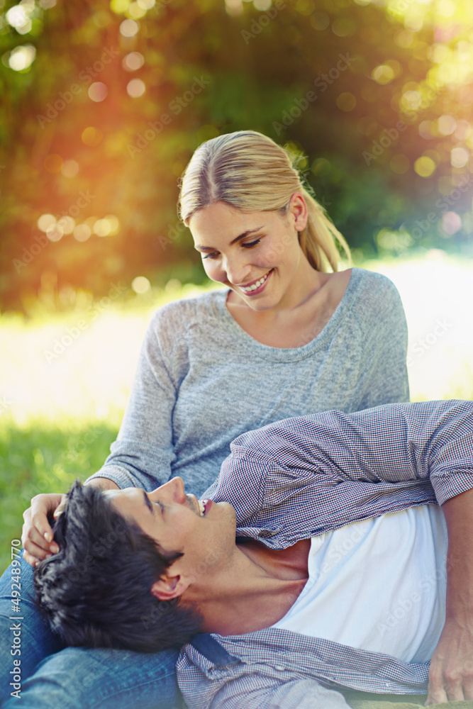 Love just fell into her lap. Shot of a happy young couple lying on the grass and sharing an affectio