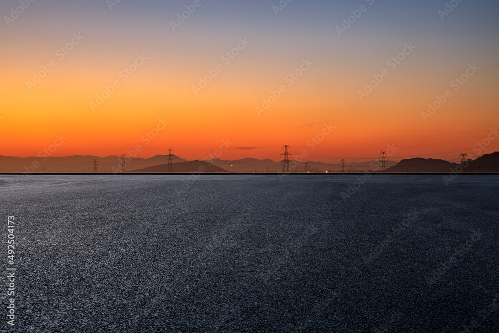 Asphalt road platform and mountain with high voltage power tower scenery at sunrise