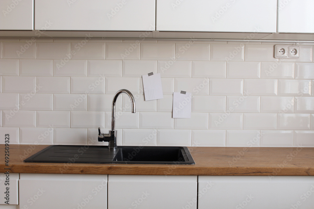 Modern kitchen. Blank paper card mock-up taped on white tiles wall. Home concept.