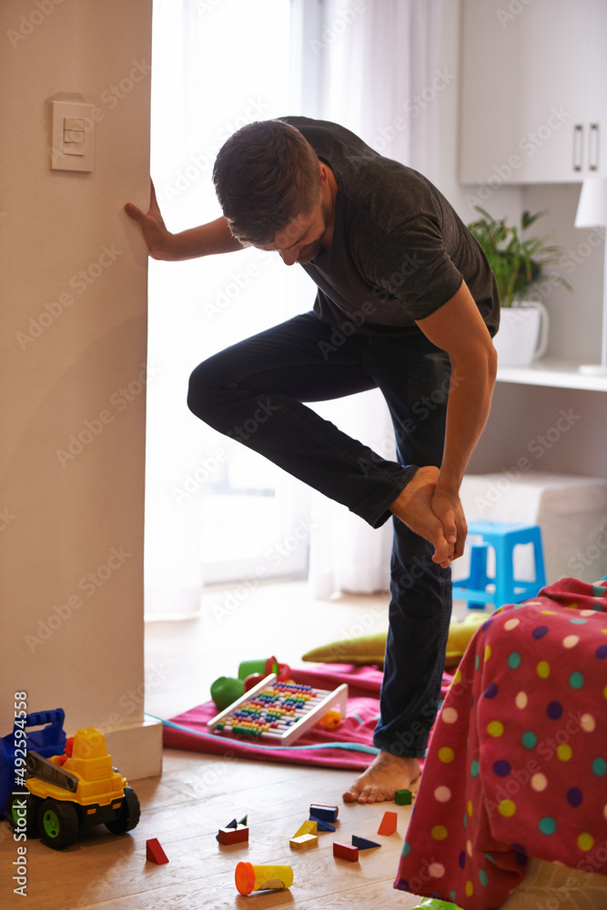 Ow I really hate it when that happens.... Shot of a man grabbing his foot in pain after standing on 