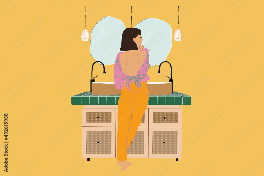 Young woman taking care of herself in the bathroom, standing back near table top with sinks and mirr