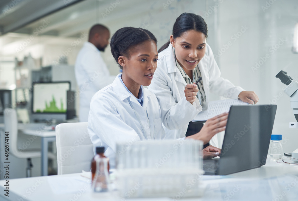 Improving lives one collaboration at a time. Shot of two young scientists using a laptop in a labora