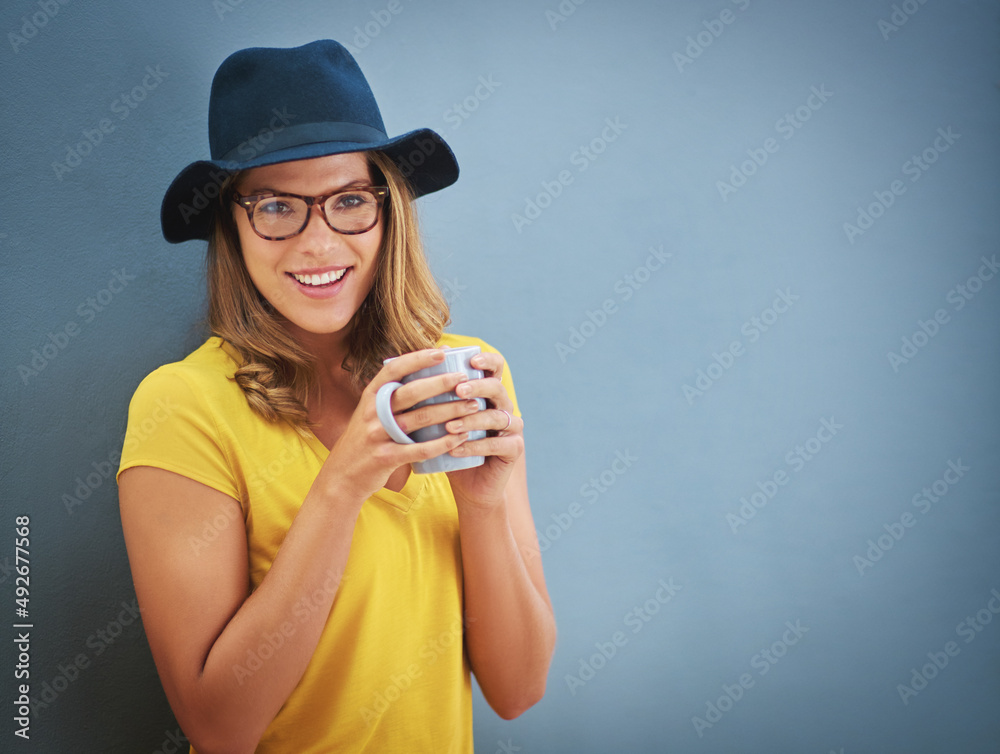 Everything gets better with coffee. Portrait of a young woman drinking a cup of coffee against a gre