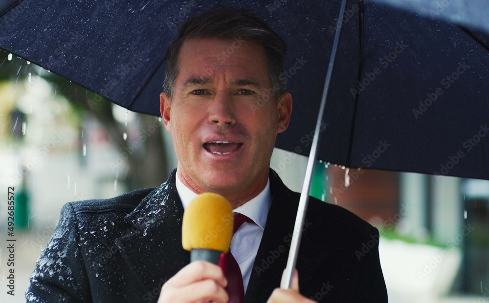 Its a very gloomy day in the city today. Portrait of a mature male reporter holding a microphone and