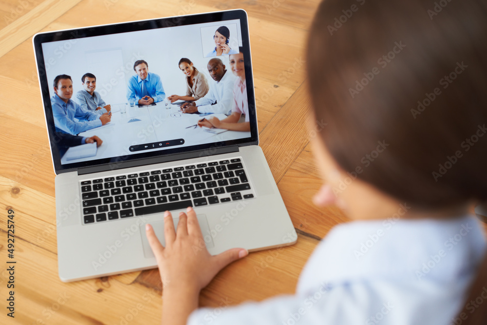 Video conference in progress.... Rear view of a young businesswoman in a video conference with her c