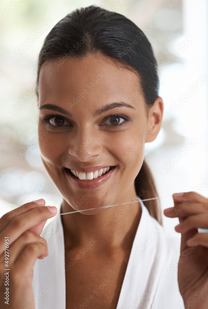 Its just part of my routine. Portrait of an attractive young woman holding dental floss and smiling.