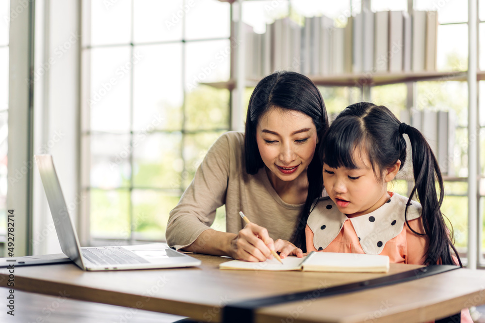 肖像快乐爱亚洲家庭母亲教小女儿亚洲女孩在桌子上学习和学习。莫