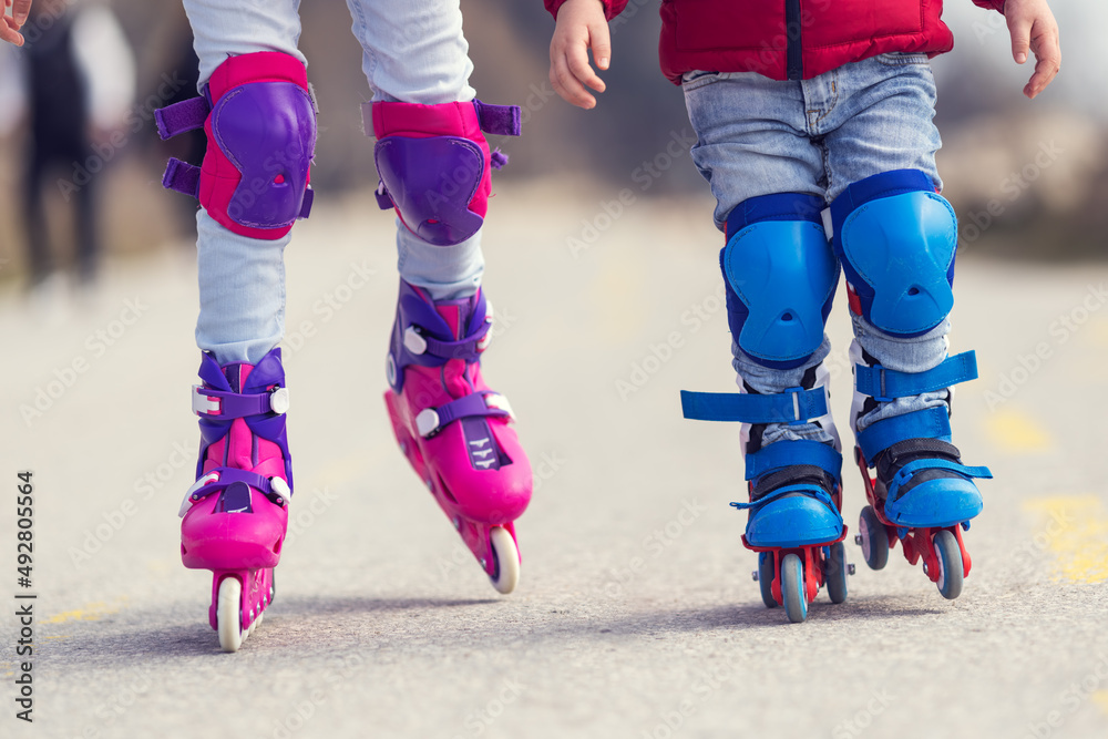 Kids boy and girl having fun outdoor while riding roller skates. Children on rollerblades. Roller sk