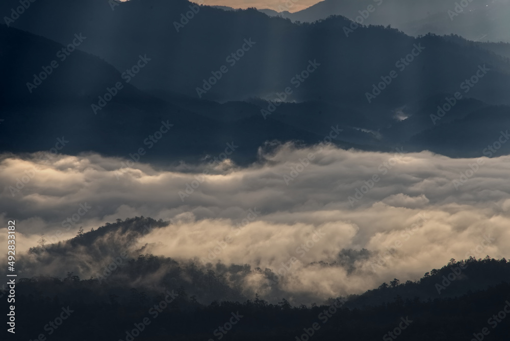 Beautiful sunlight ray over a mountain range and sea of fog in a valley