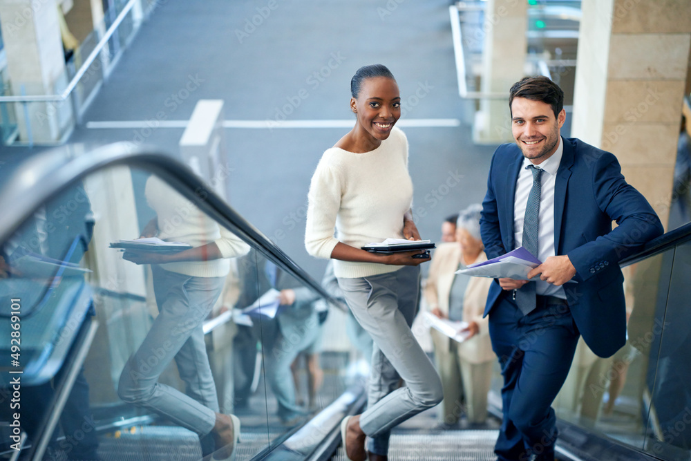 Rising to the top with ease. Portrait of a young businesswoman and her male colleague on the escalat