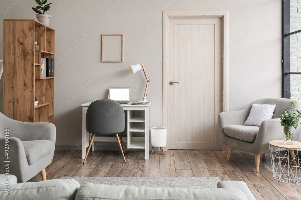 Interior of light living room with wooden bookcase and modern workplace