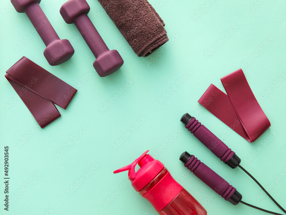 Sports equipment, bottle of water and towel on color background