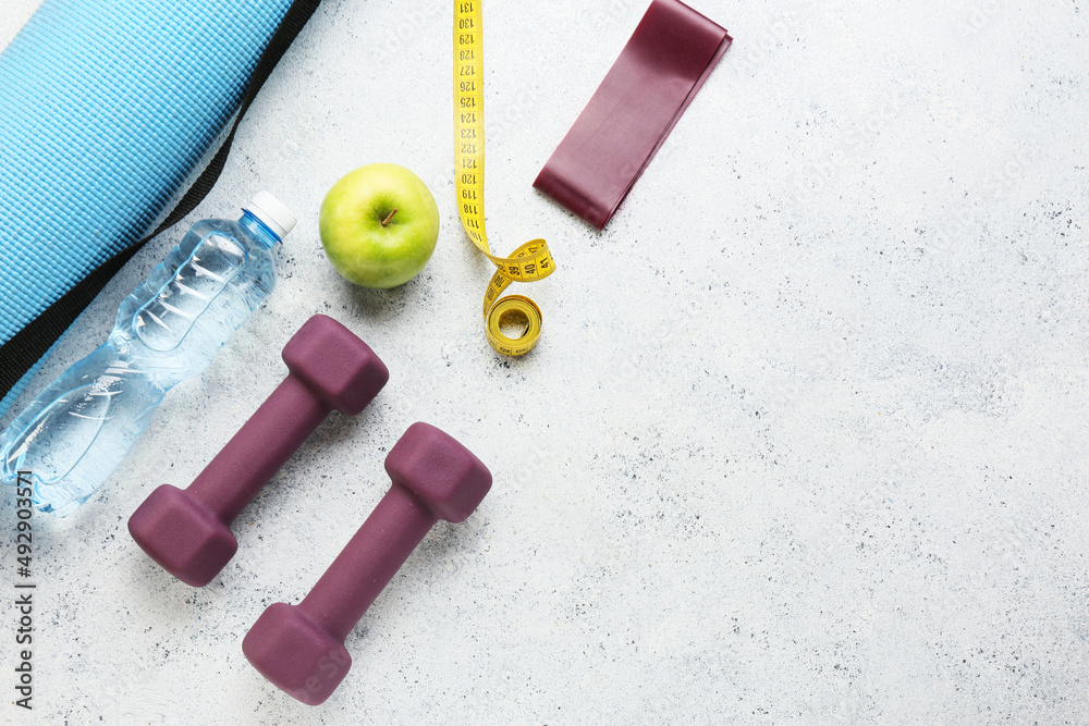 Stylish sport equipment and apple on light background