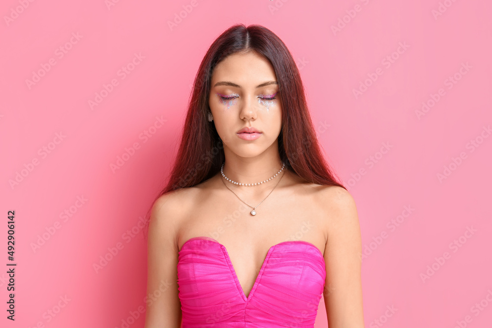 Beautiful young woman with creative makeup and closed eyes on pink background