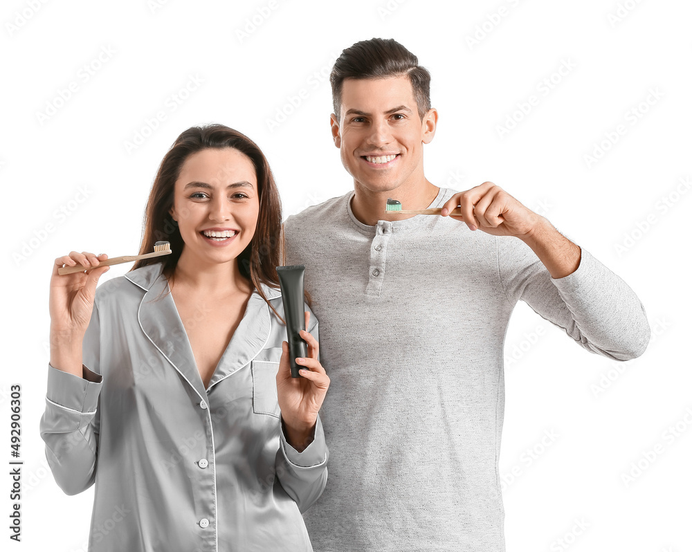 Young couple brushing teeth with activated charcoal tooth paste on white background