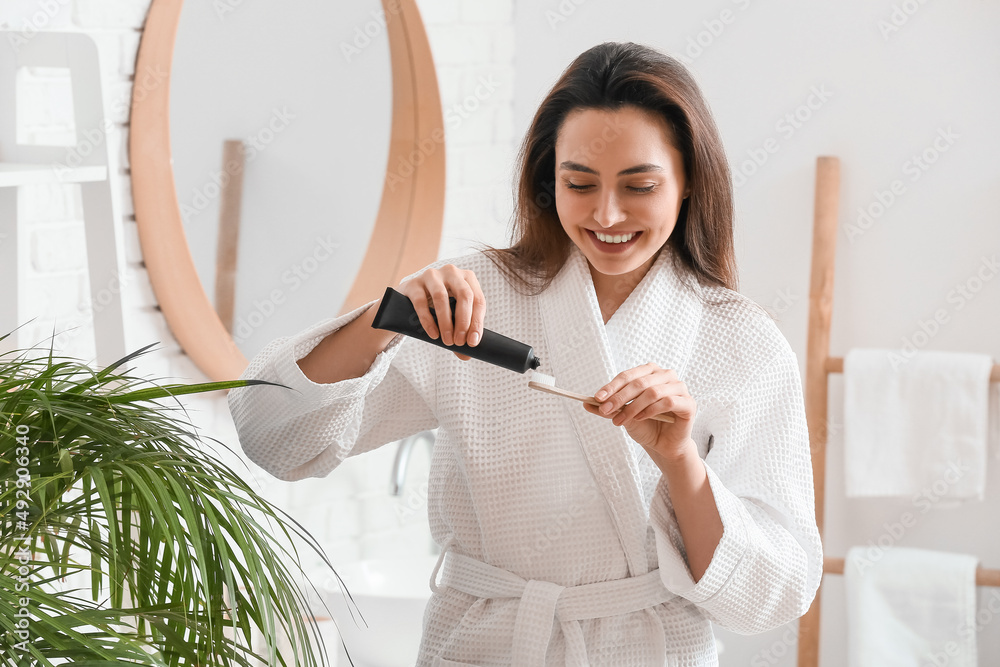 浴室里有活性炭牙膏和刷子的漂亮年轻女人