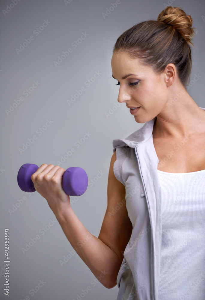 Strengthening her biceps. A young woman working out with weights.