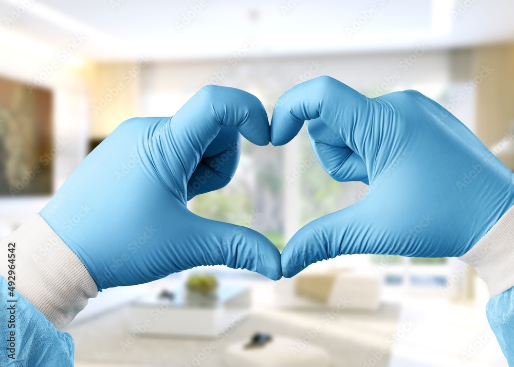 Young doctor cardiologist showing heart symbol with fingers, expressing love and support to patients