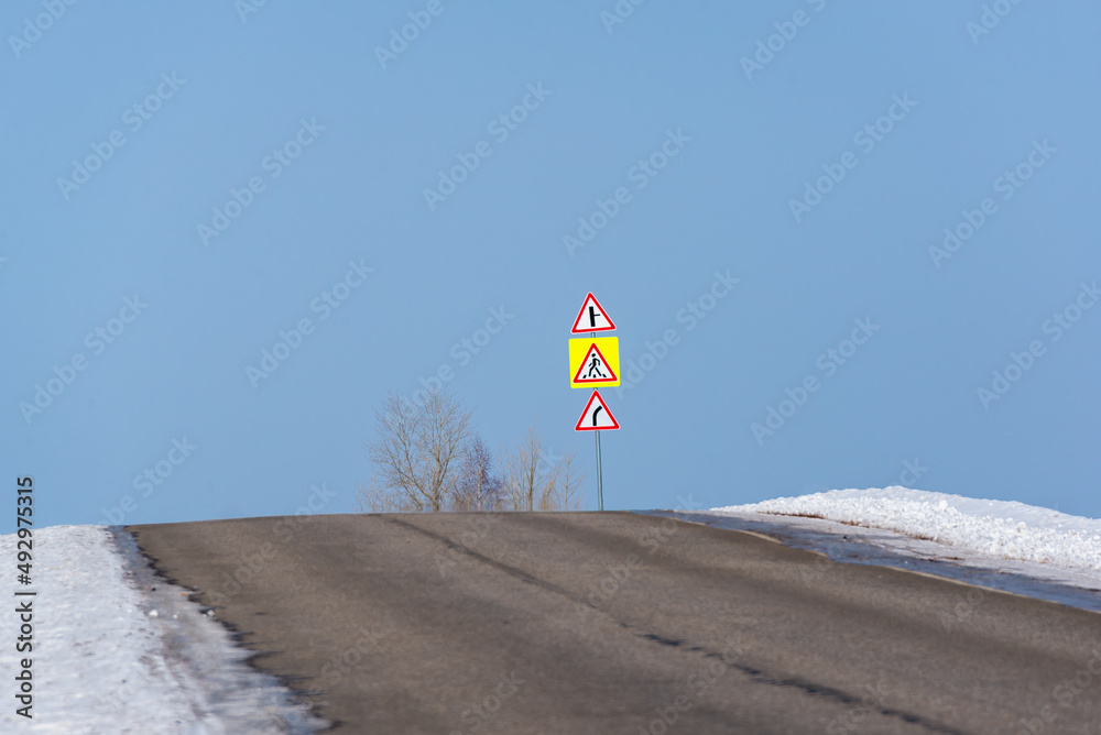 The road and the edges of the snow and road signs.