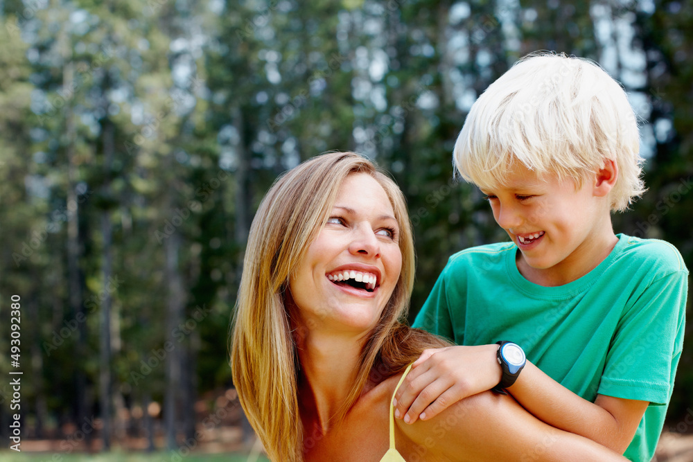 Mother giving piggyback ride to her son. Beautiful woman giving a piggyback ride to her son during h