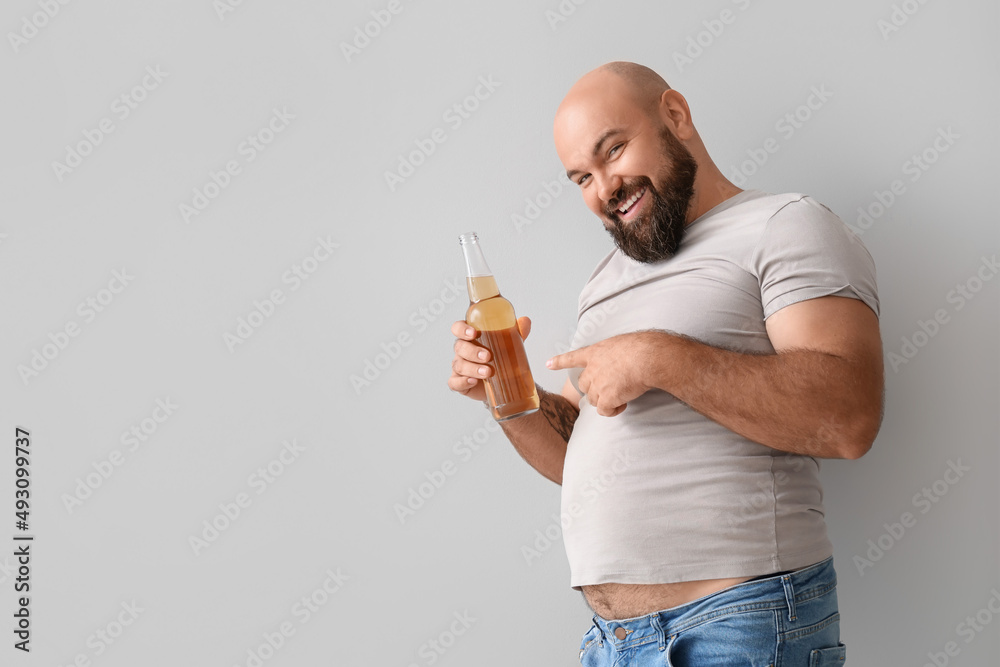 Happy bald man with beer on light background