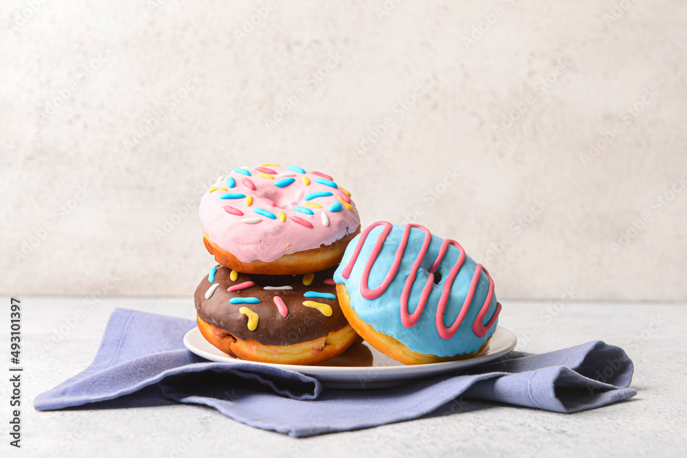 Plate with delicious donuts on light background