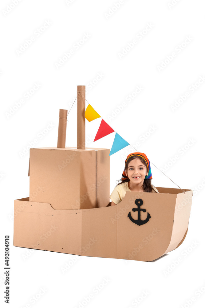 Funny little girl playing with cardboard ship on white background