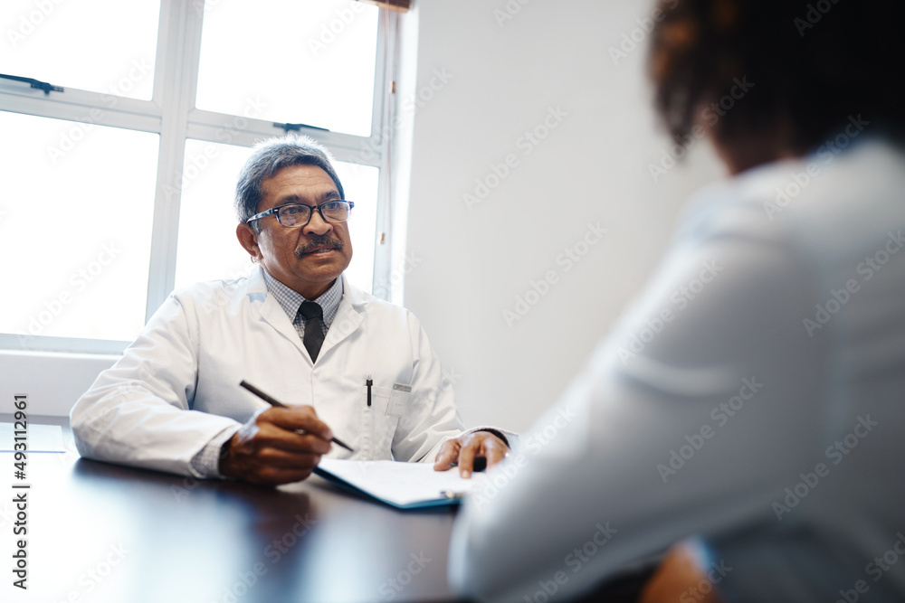 Tell me more about your symptoms.... Shot of a mature doctor having a consultation with a patient in