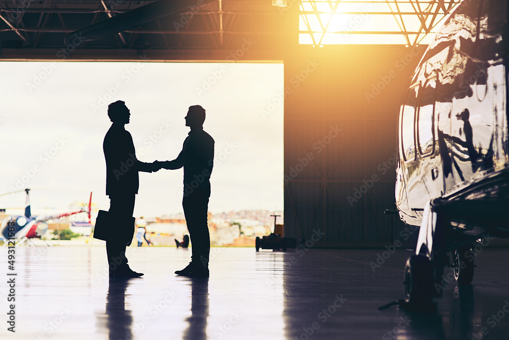 Welcome home. Full length shot of two unrecognizable businessmen shaking hands while standing in a h