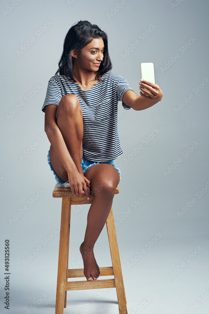 Darling, youre different. Studio shot of a beautiful young woman taking a selfie while sitting on a 