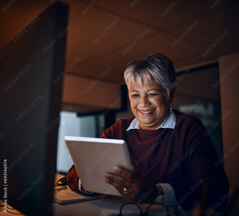 Getting through some overtime with some smart apps. Shot of a mature businesswoman using a digital t