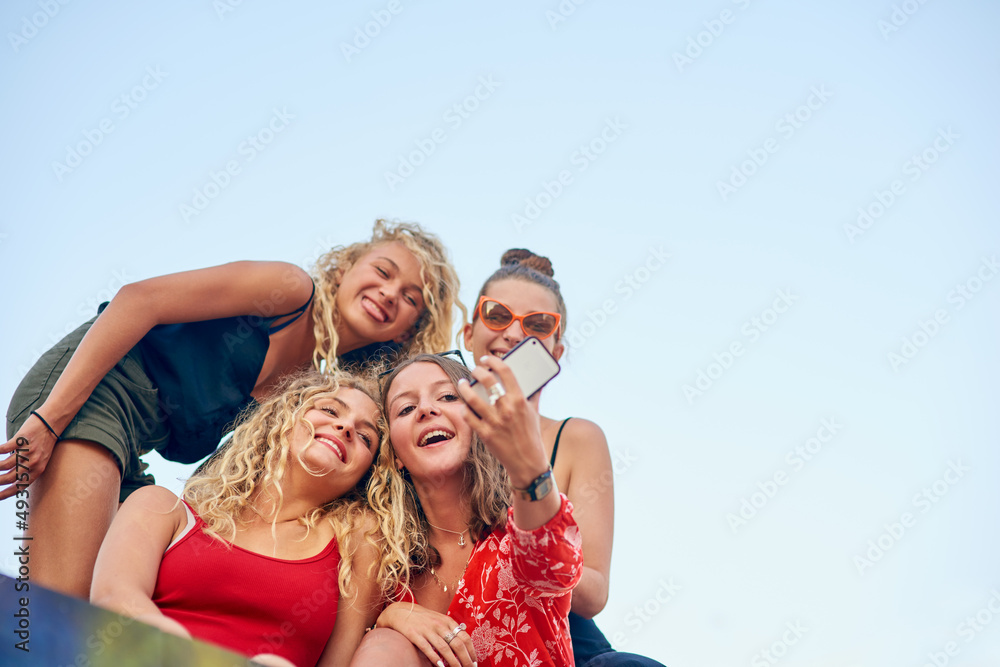 Its all about the angle. Low angle shot of a group of attractive young girlfriends taking selfies in