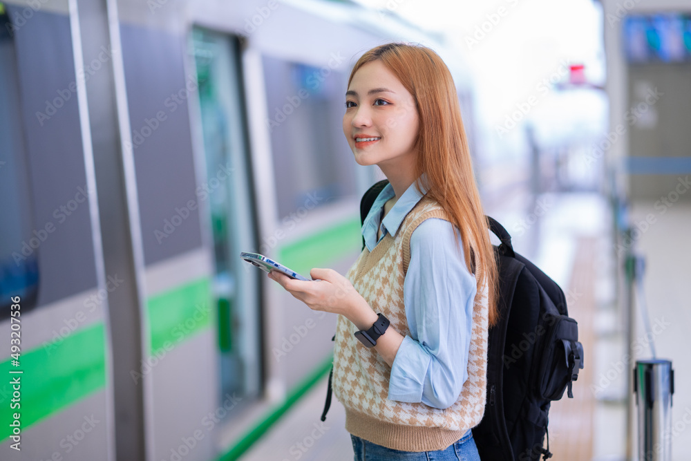 年轻的亚洲女孩在车站等火车