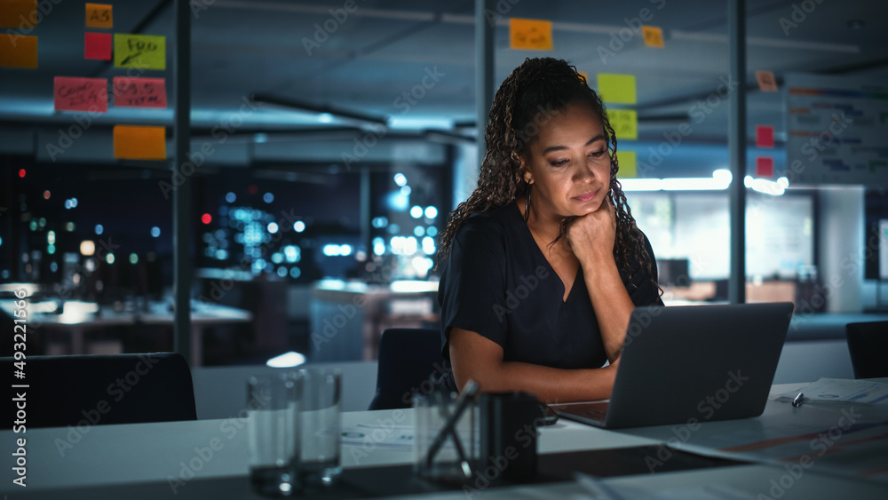 Portrait of African American Businesswoman Working on Laptop Computer in Big City Office Late in the