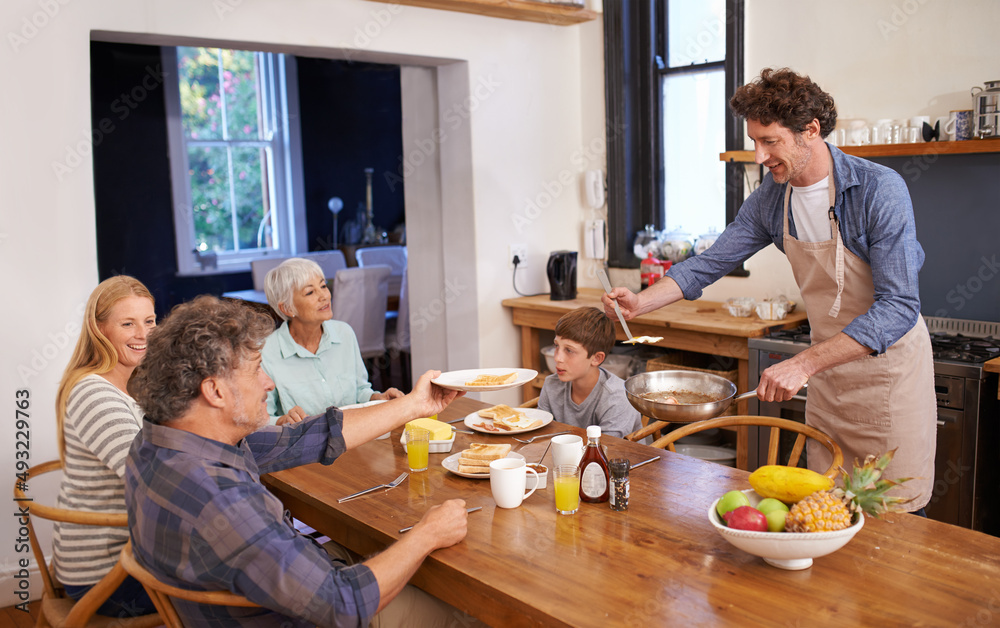 Seconds for grandpa. A cropped shot of a happy man serving his family a deliciously cooked breakfast