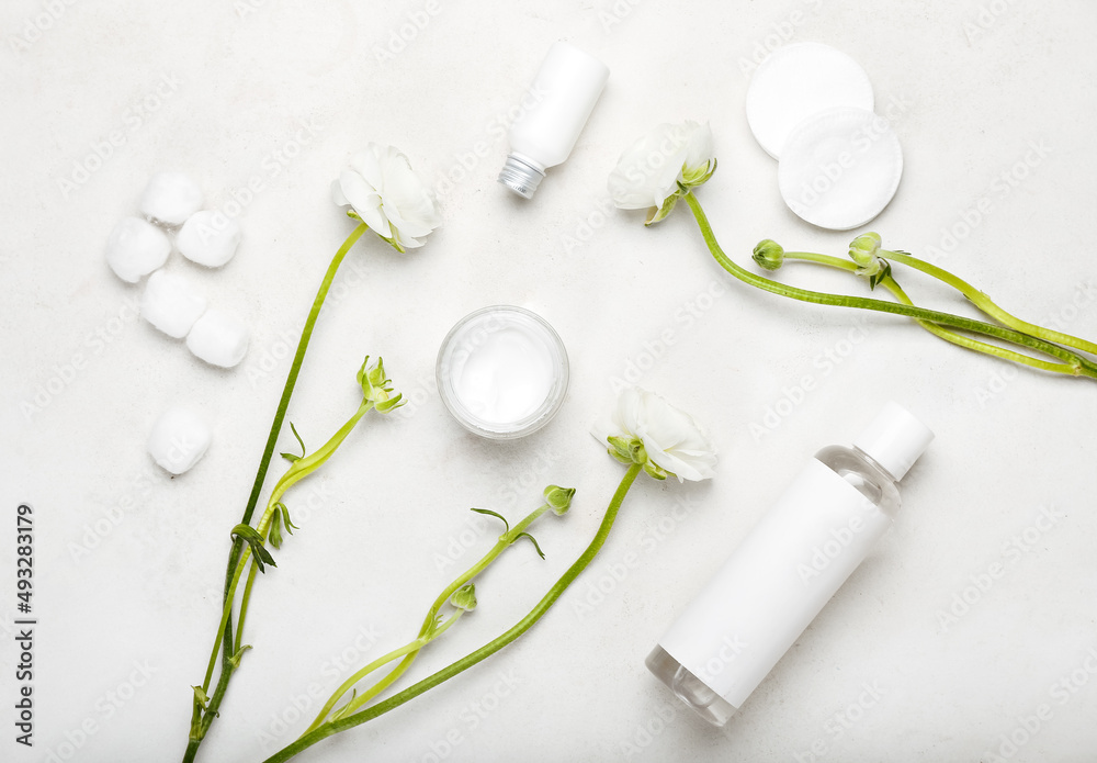 Composition with cosmetic products, cotton pads, balls and ranunculus flowers on light background