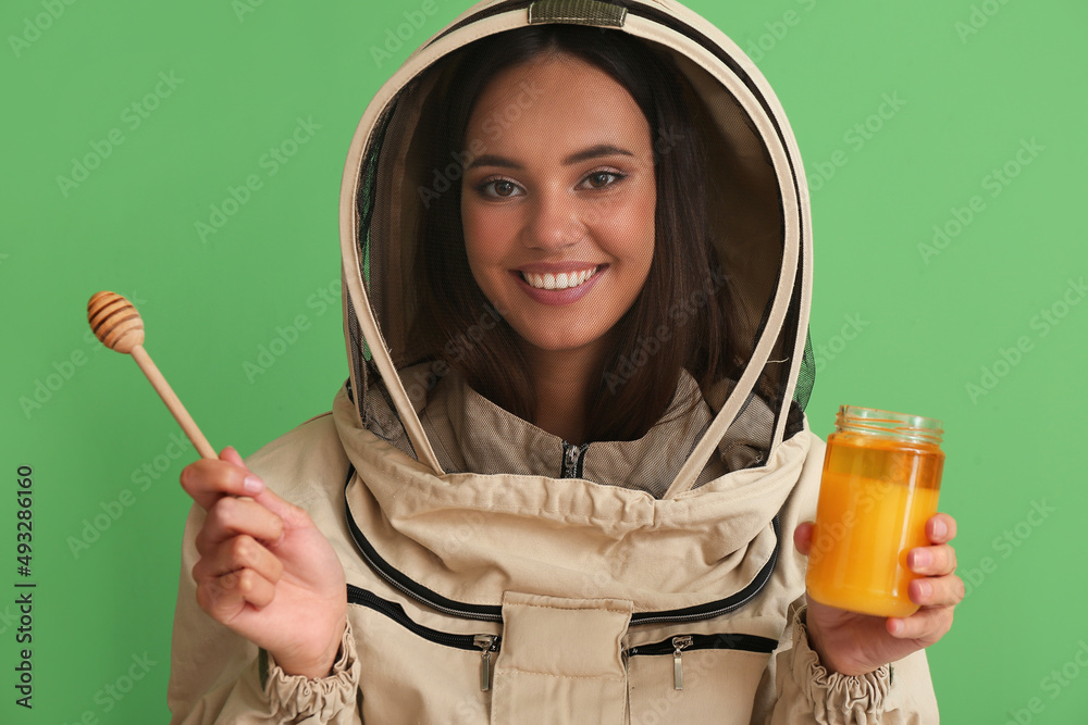 Female beekeeper with honey on color background