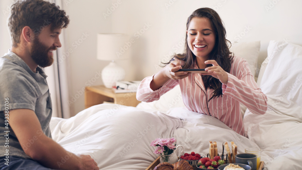 This is why I married him. Shot of a young woman taking a picture of the breakfast her husband has s