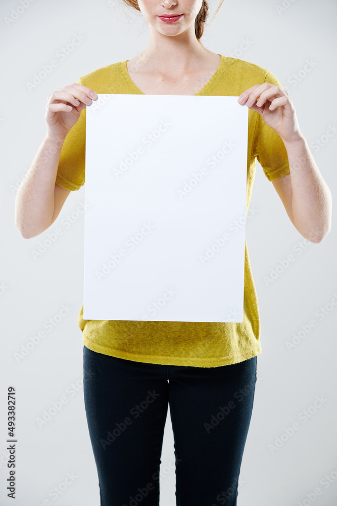 Giving you some space. Cropped studio shot of a young woman holding up a white placard with copyspac