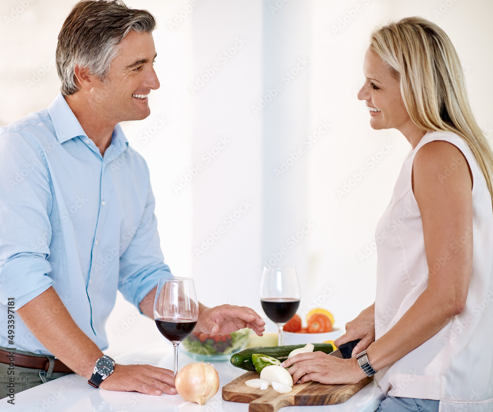 Cooking and bonding. Cropped shot of a mature couple enjoying wine and talking while making dinner t