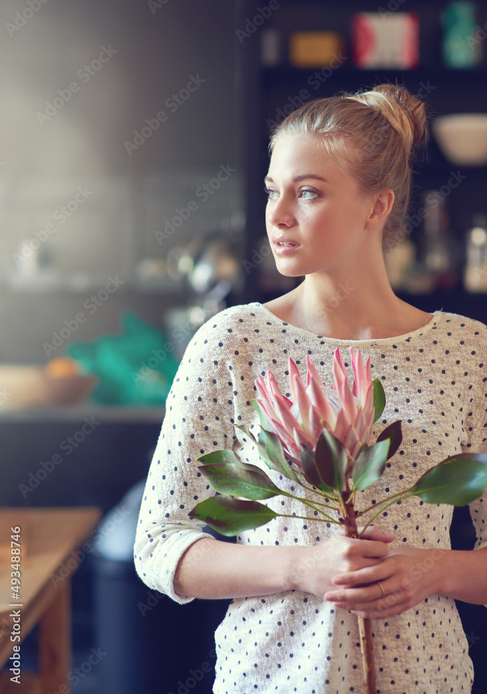 花卉灵感。一位美丽的年轻女子站在厨房里，手里拿着一朵变形花。