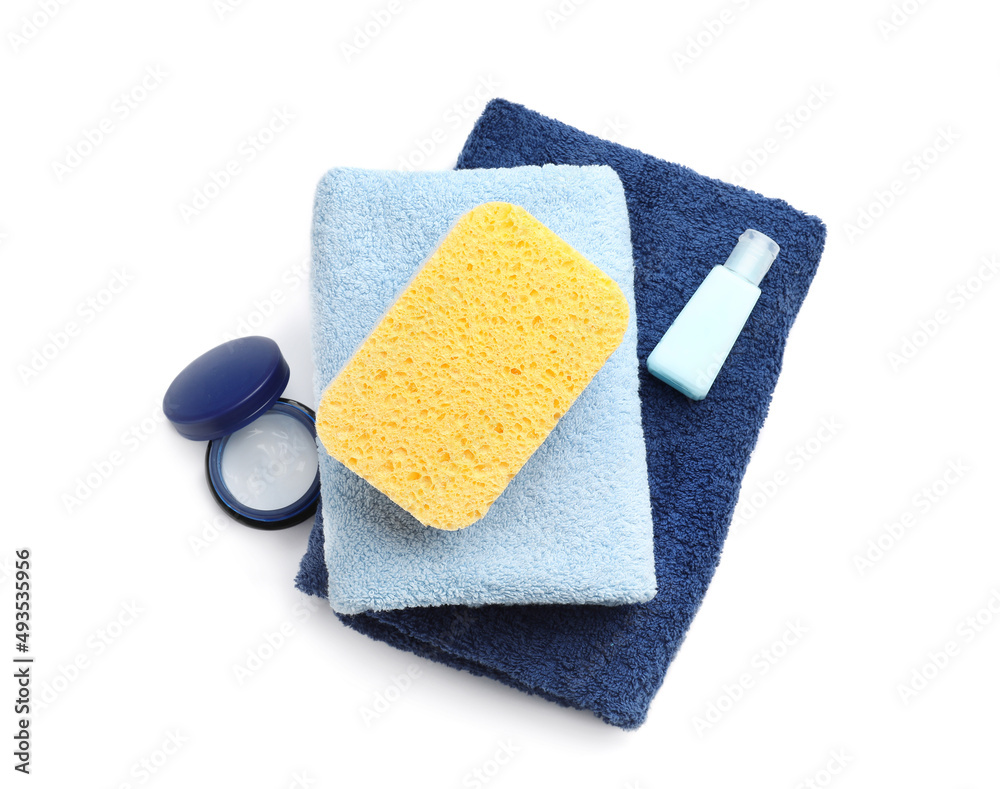 Towels, bath sponge and jar of cosmetic product on white background