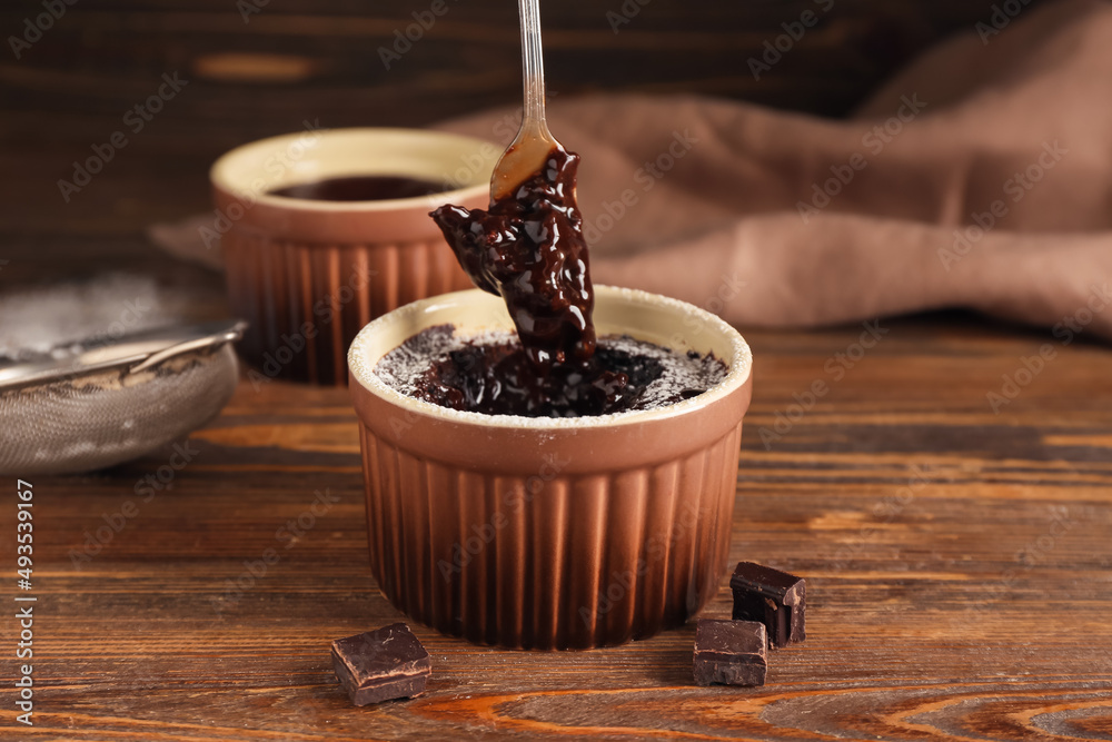 Ramekin with tasty lava cake on wooden background